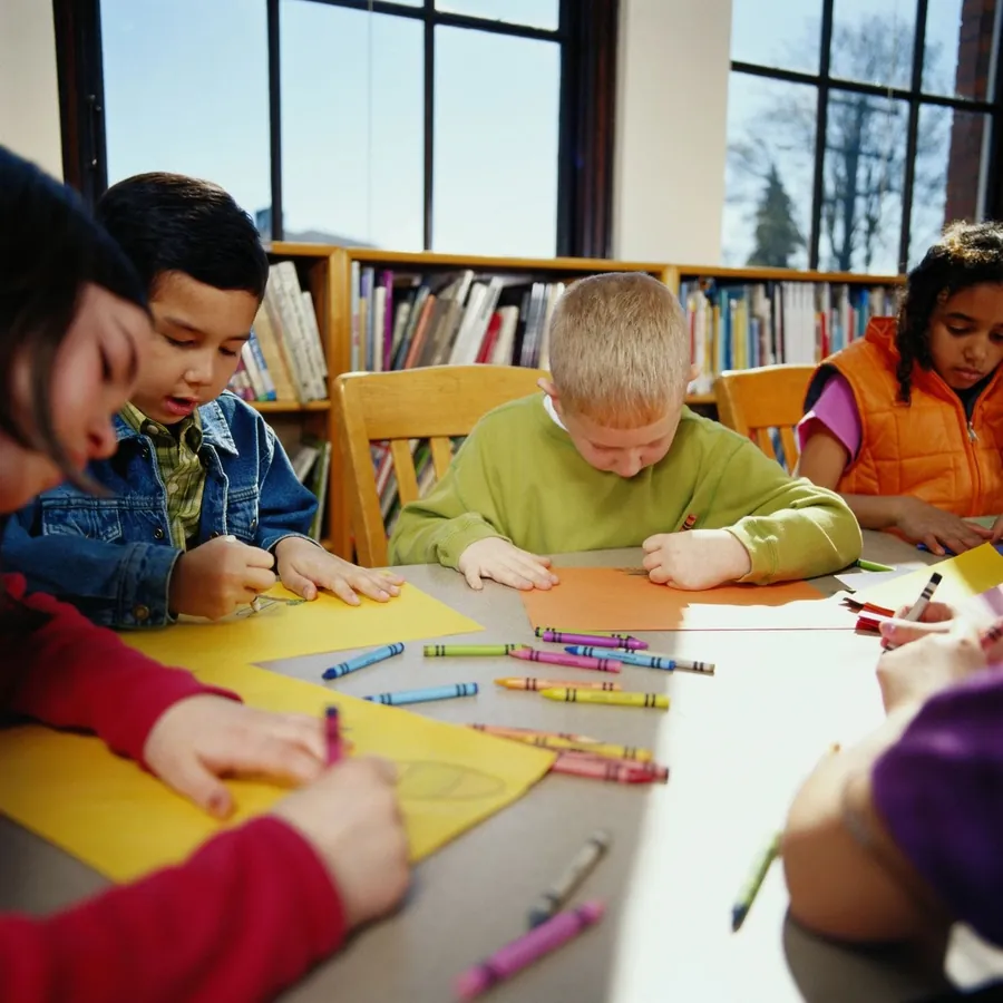 Children drawing with crayons at a library table.